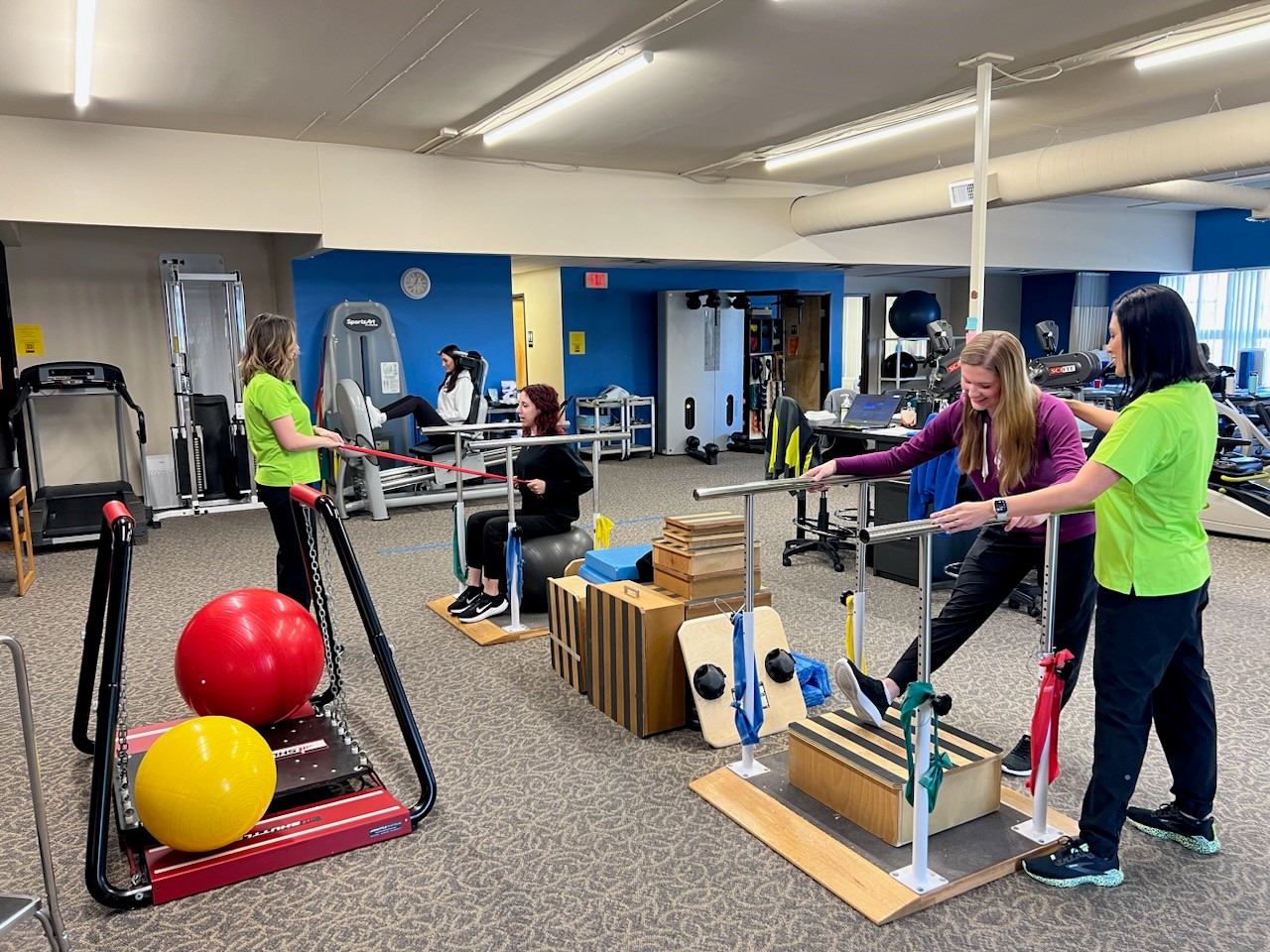 Picture of spacious exercise area with patients and therapists engaged in balance and strength exercises.