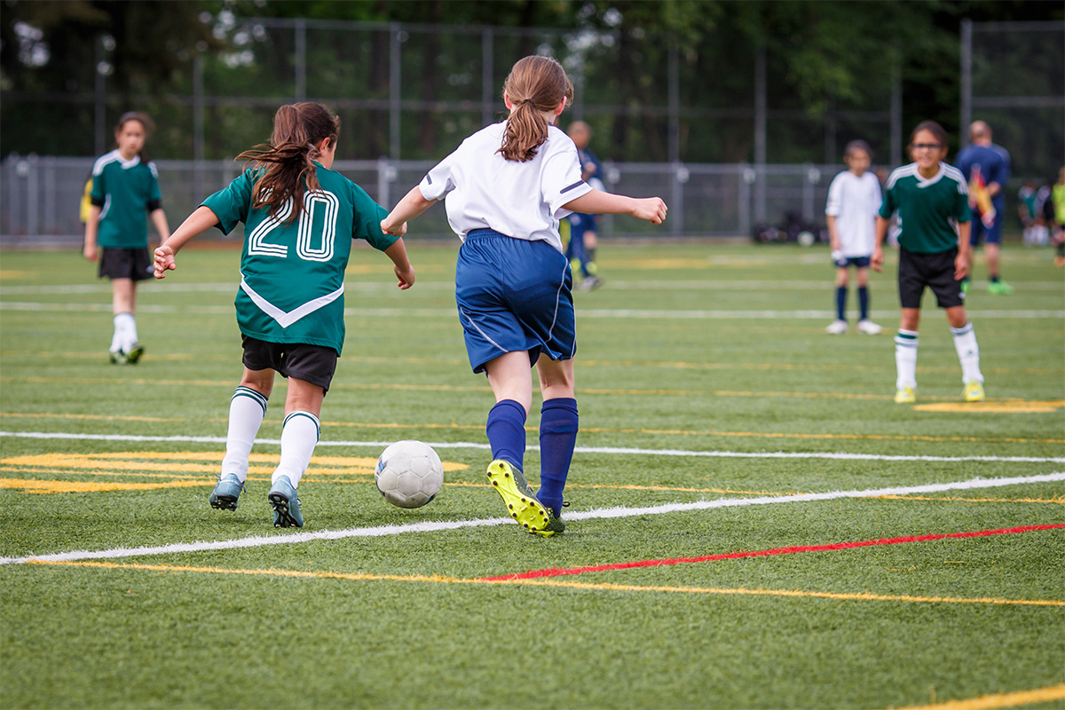 Girls' competitive soccer game played on artificial turf.