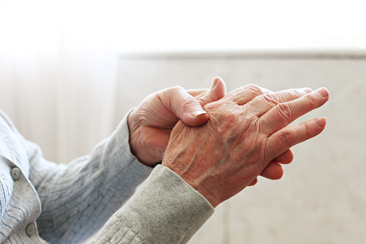 Picture of elderly woman rubbing her hands to relieve the pain.